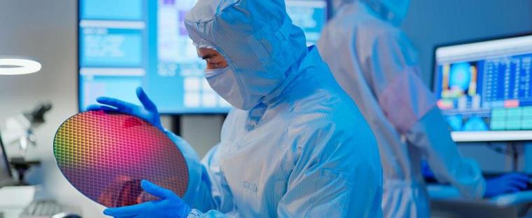 Worker holding a semiconductor wafer.